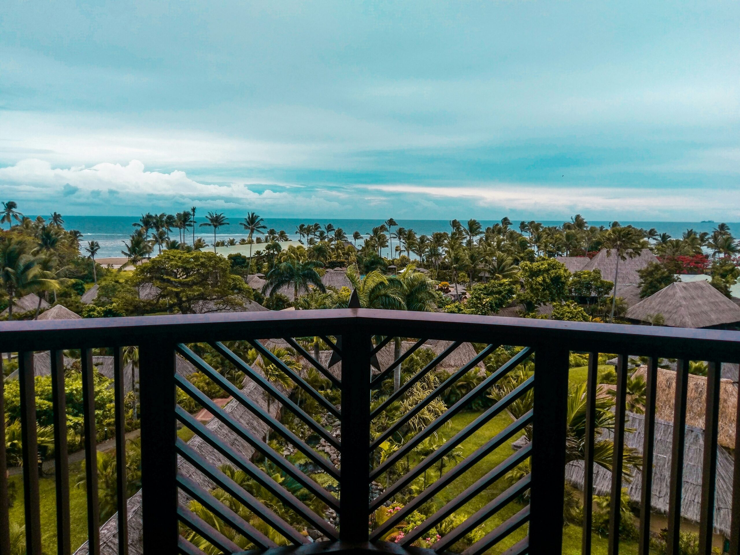 wide-angle photography of brown huts surrounded by coconut palm trees during daytime